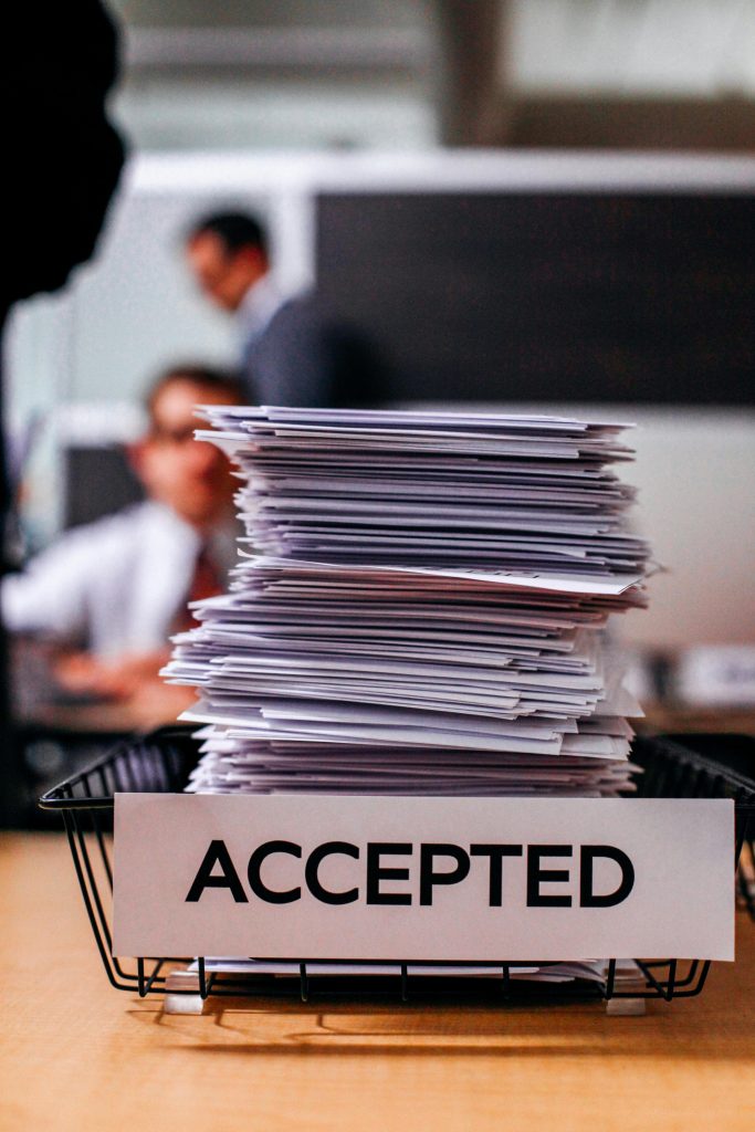pexels photo 2928232 2928232 Pile of papers with 'Accepted' label in a busy office setting, highlighting information management.